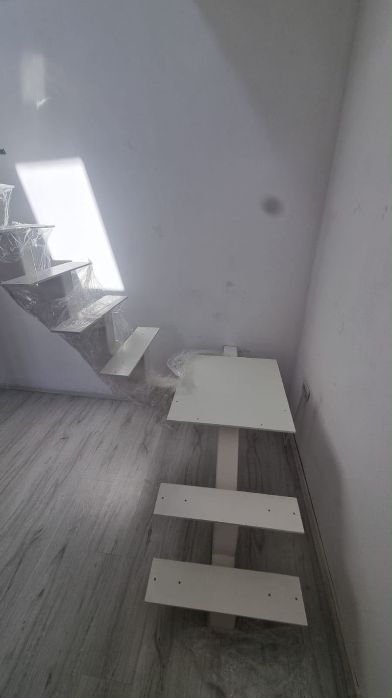 Scară interioară albă pe grindă centrală, cu trepte în consolă